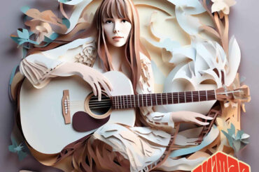 Joni Mitchell sitting on the floor with an acoustic guitar, posing for the camera.